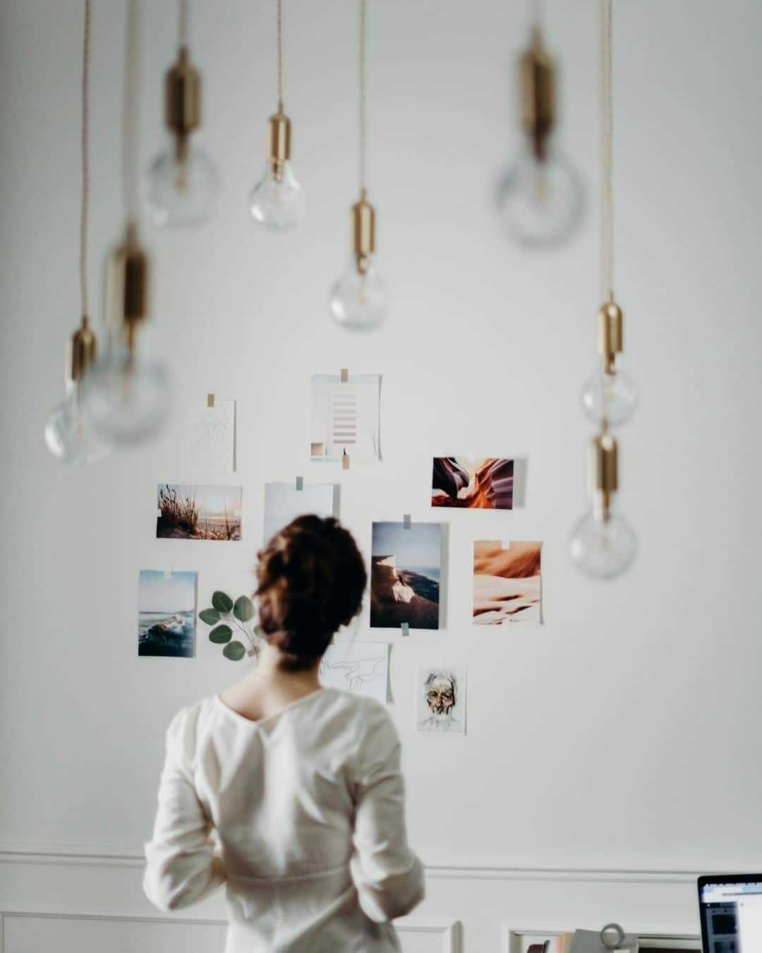 Femme de dos observant un moodboard d&rsquo;inspirations visuelles, illustrant la cr&eacute;ation d&rsquo;une identit&eacute; de marque coh&eacute;rente.