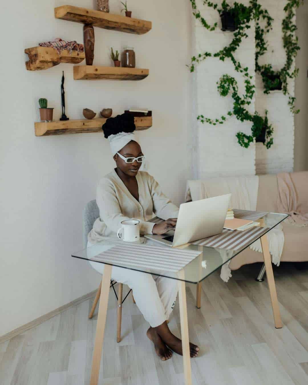 Femme concentr&eacute;e sur son ordinateur dans un int&eacute;rieur naturel, symbolisant le travail strat&eacute;gique sur la pr&eacute;sence digitale.