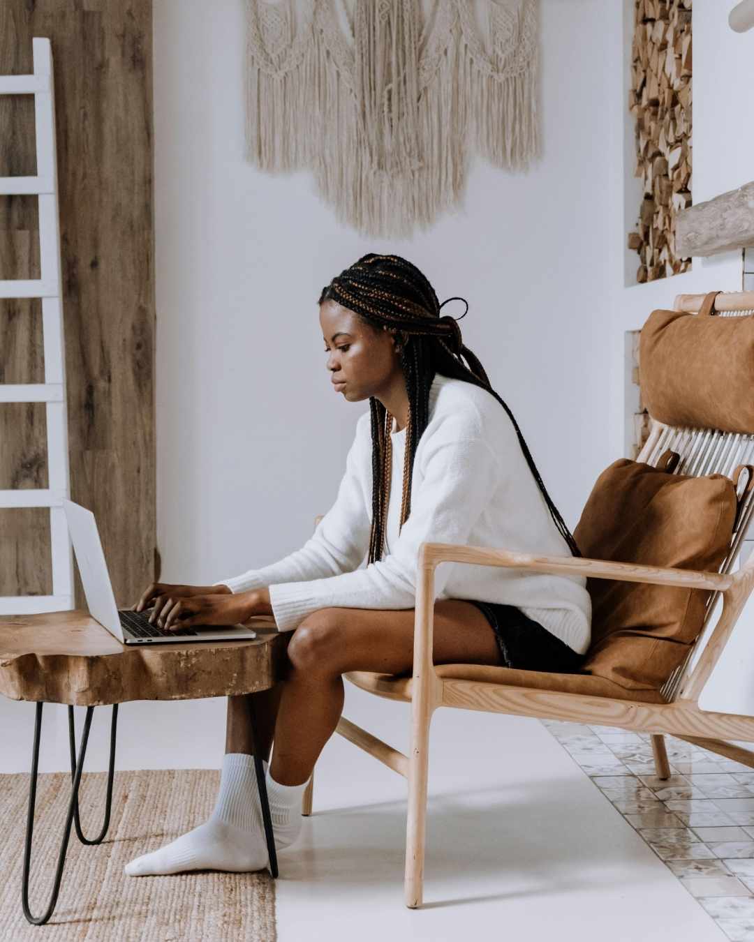 Femme concentr&eacute;e sur son ordinateur dans un int&eacute;rieur naturel, symbolisant le travail strat&eacute;gique sur la pr&eacute;sence digitale.