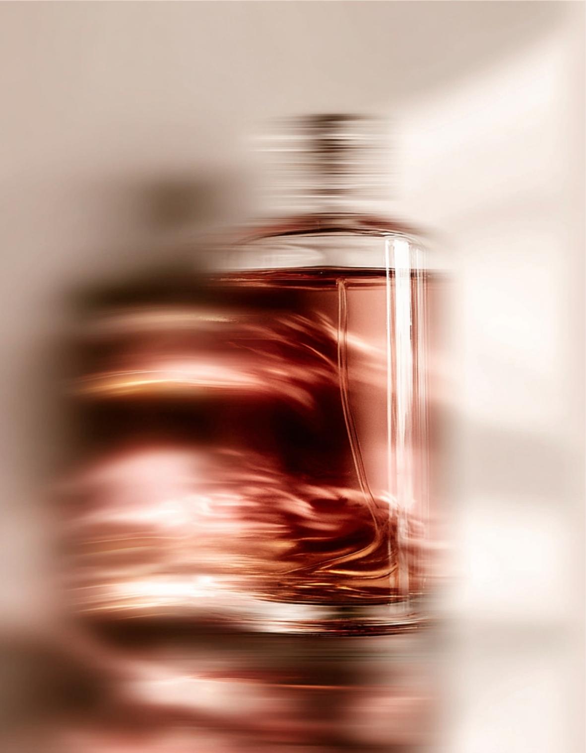 Flacon de parfum aux reflets bordeaux et ambrés dans une mise en scène artistique, illustrant l'univers sensoriel d'un studio de branding beauté et bien-être à Lyon