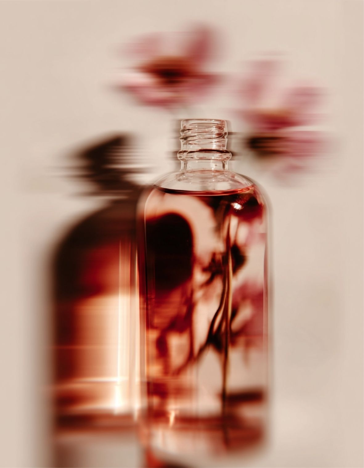 Flacon de sérum floral aux pétales roses en arrière-plan dans une ambiance lumineuse et sensorielle, identité visuelle studio de branding beauté et bien-être à Lyon